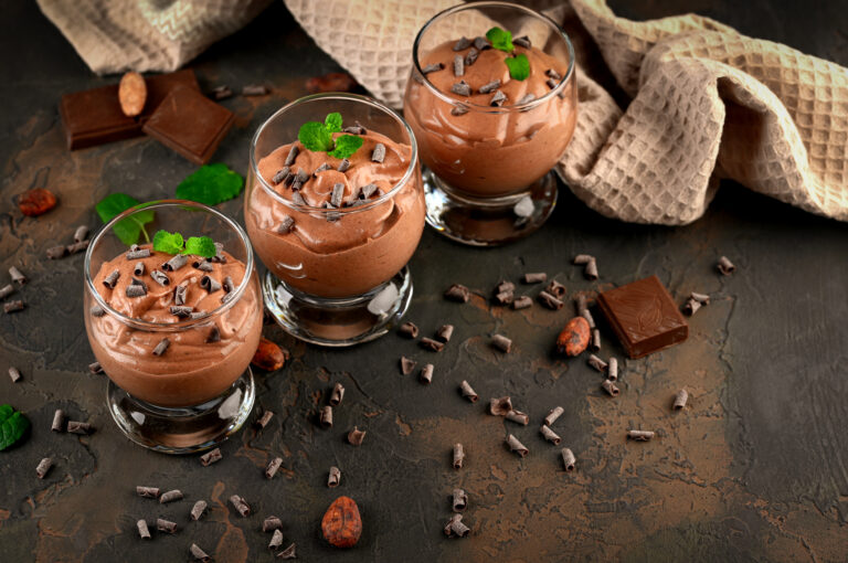 Vegan chocolate mousse with mint, bar of chocolate and cocoa beans on a dark background. Copy space